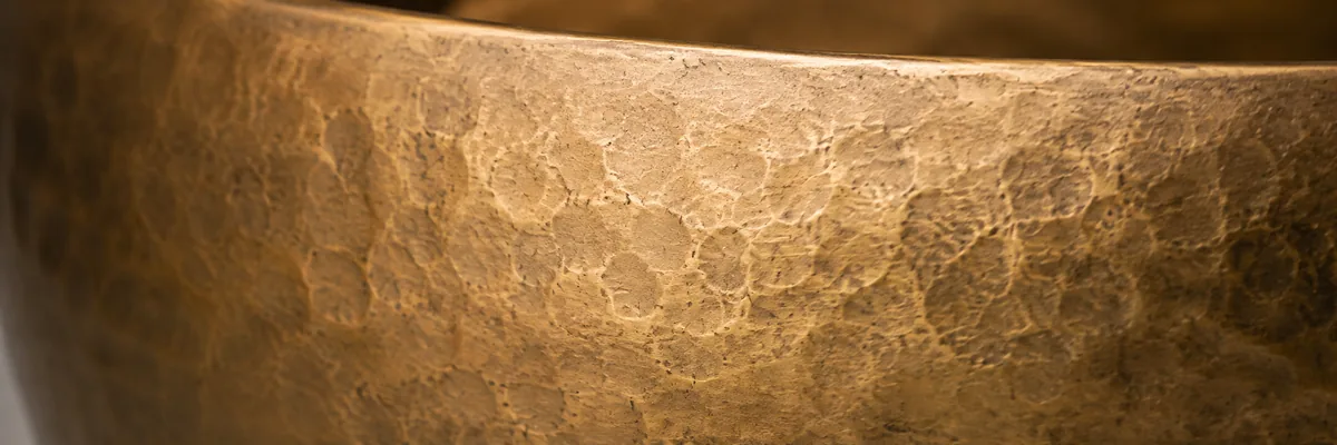 The hammered rim of an ANURAVA bell-metal instrument in close detail